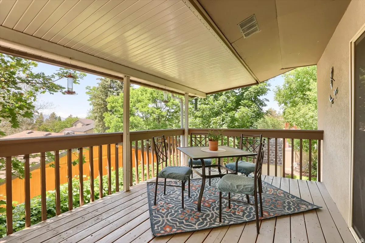 Covered outdoor deck with wood-finish flooring, wood railings, and a stucco exterior wall