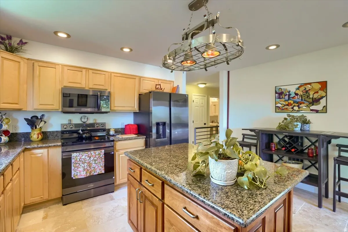 Kitchen featuring wood cabinetry, speckled countertops, stainless steel appliances, a central island, and recessed lighting