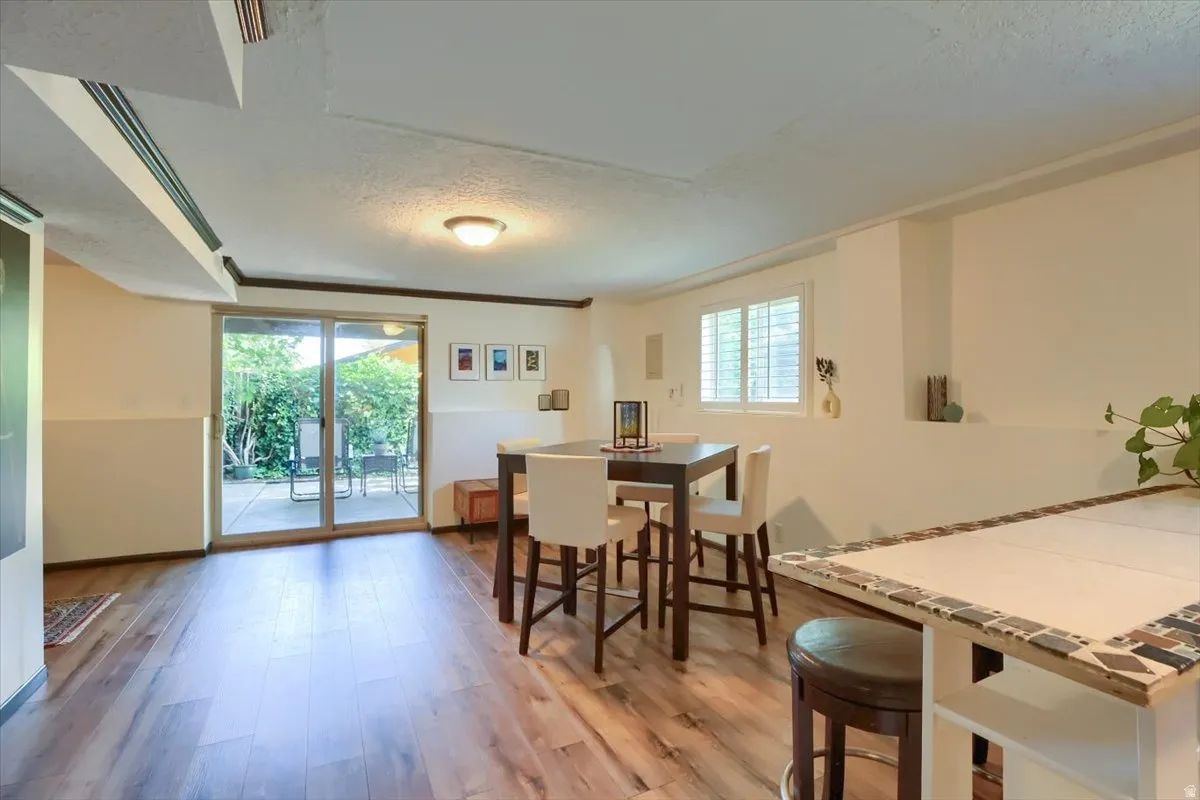 Spacious living area featuring wood-finish flooring, a sliding glass door to an outdoor patio, and a window with plantation shutters