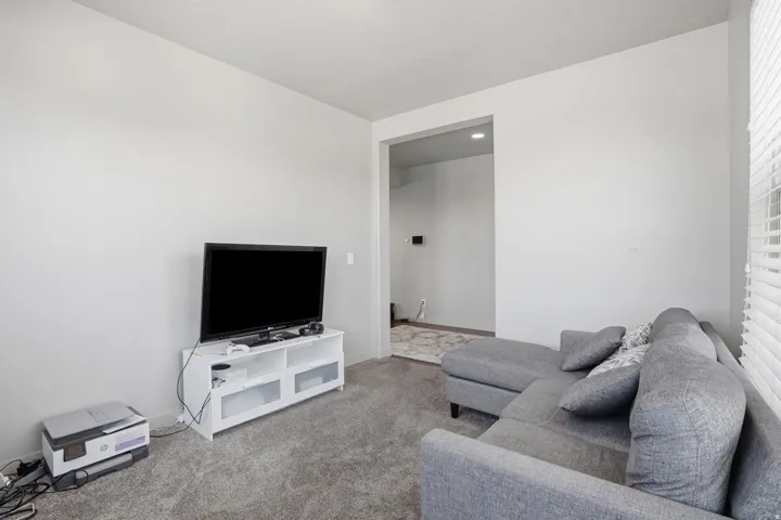 Carpeted living area with light gray walls and a cased opening