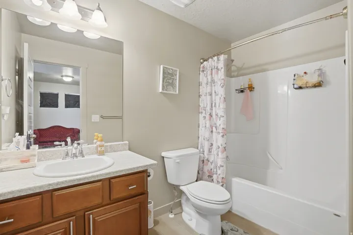 Bathroom featuring a single vanity with wood-finish cabinetry, a white basin, and a speckled countertop