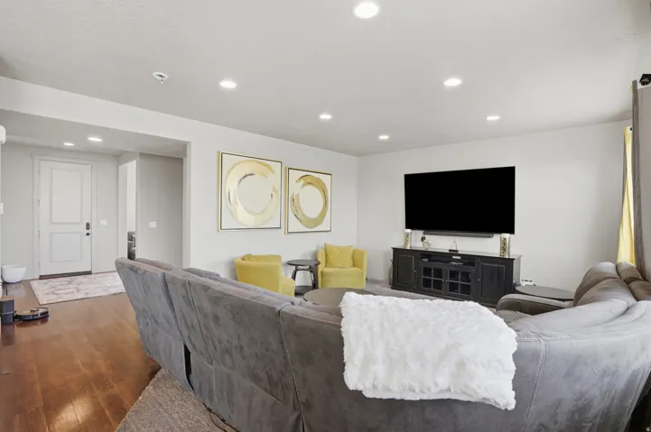 Spacious living area featuring rich wood-finish flooring, recessed lighting, and a neutral color palette