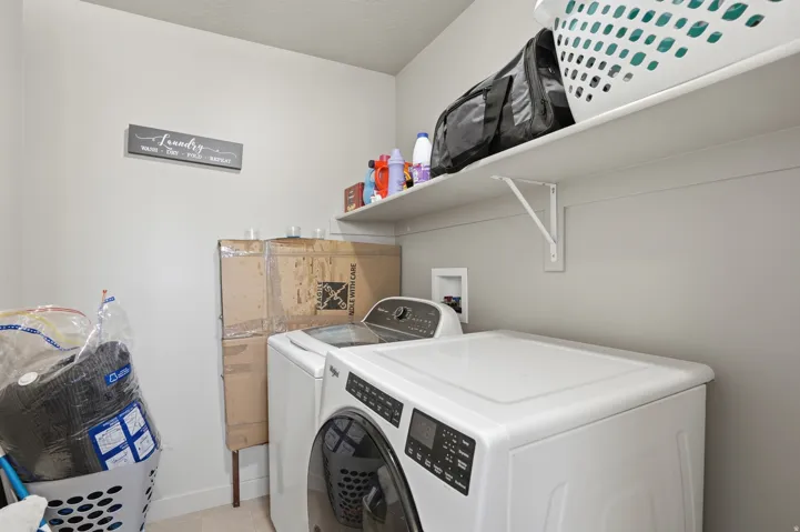 Dedicated laundry area featuring a full-sized washer and dryer, ample wall shelving, and neutral wall tones