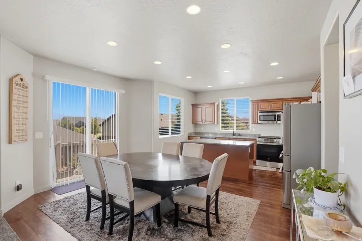 Open-concept kitchen and dining area featuring wood-finish flooring, recessed lighting, and a sliding glass door