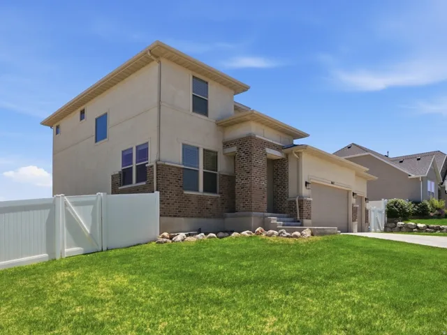 Two-story residence featuring light-colored stucco and brick facade accents