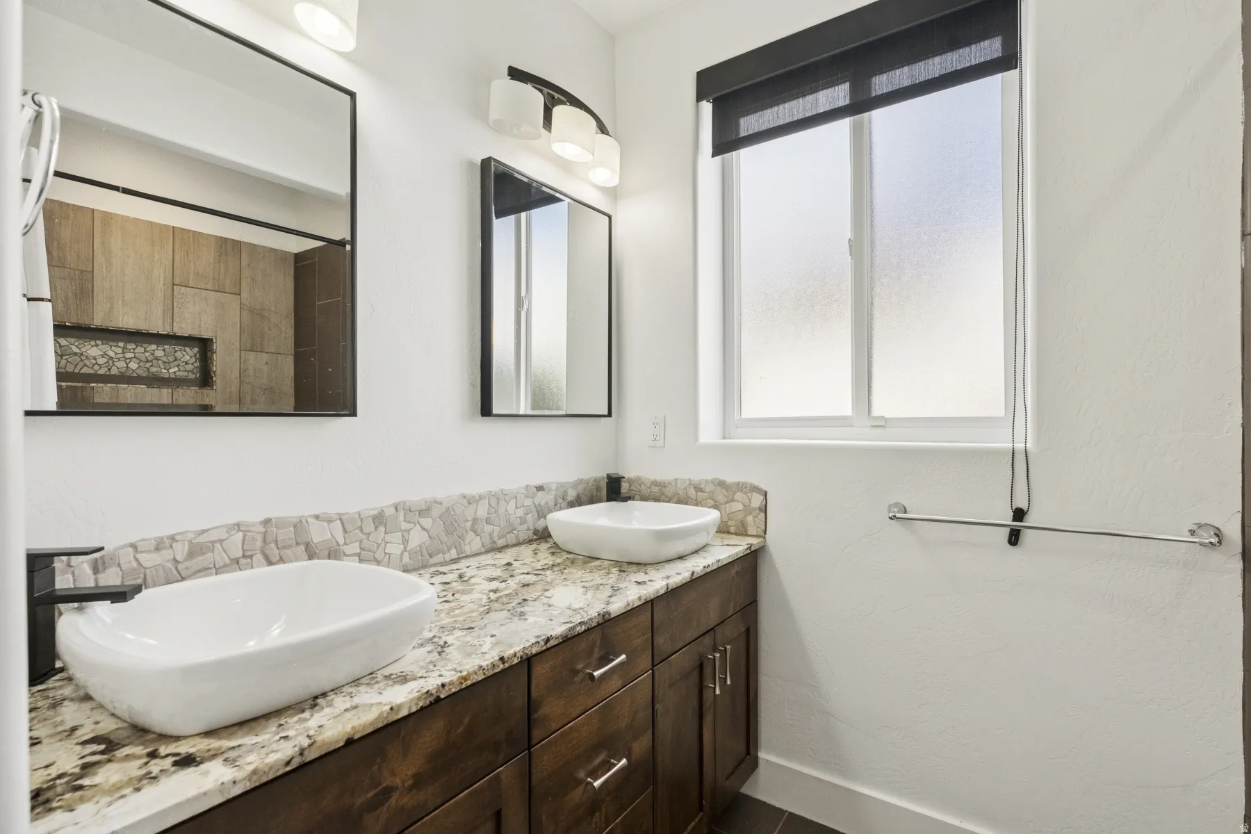 Bathroom featuring double vanity and tiled shower