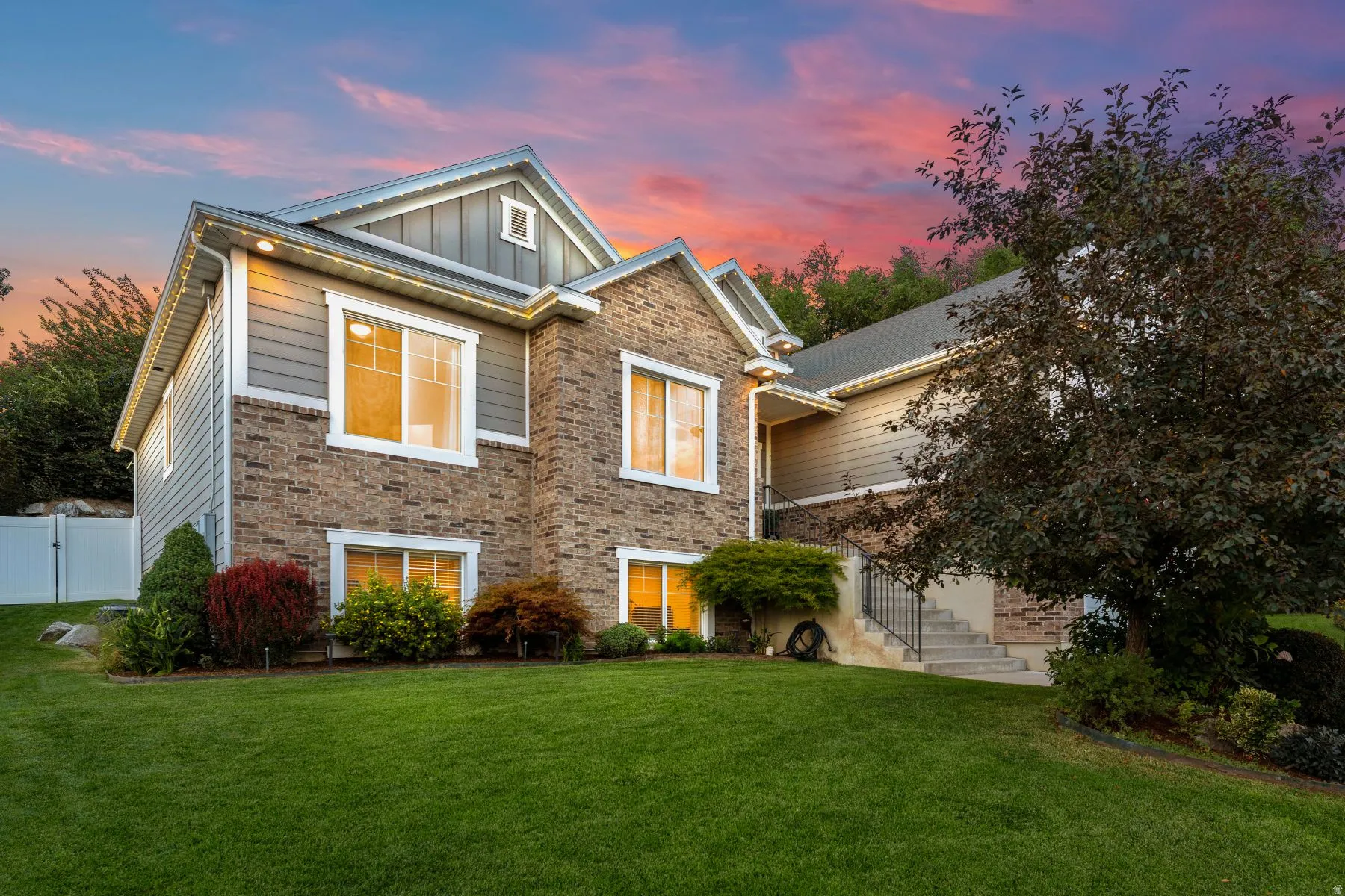 View of front of home featuring board and batten siding, a lawn, and brick siding