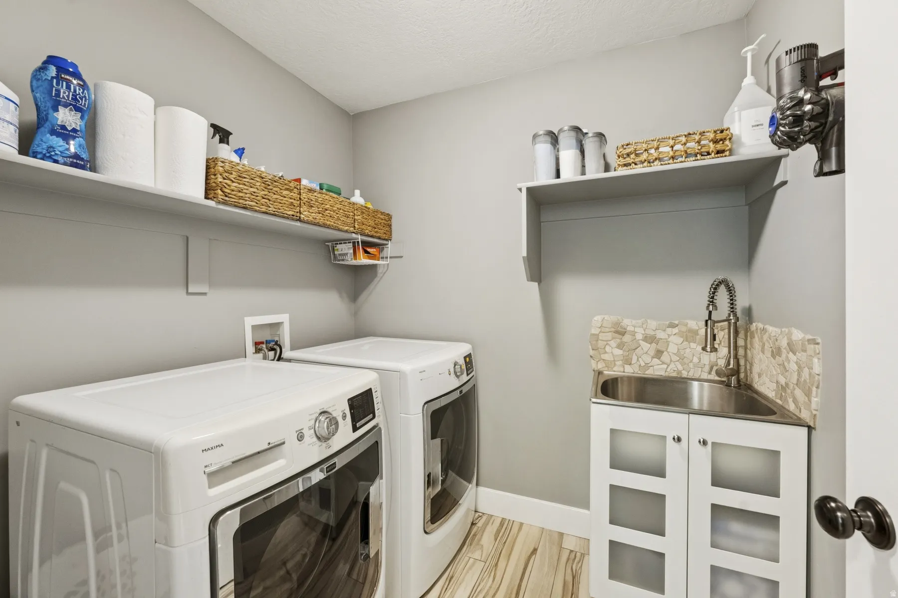 Laundry room with washer and dryer, light wood finished floors, and a textured ceiling