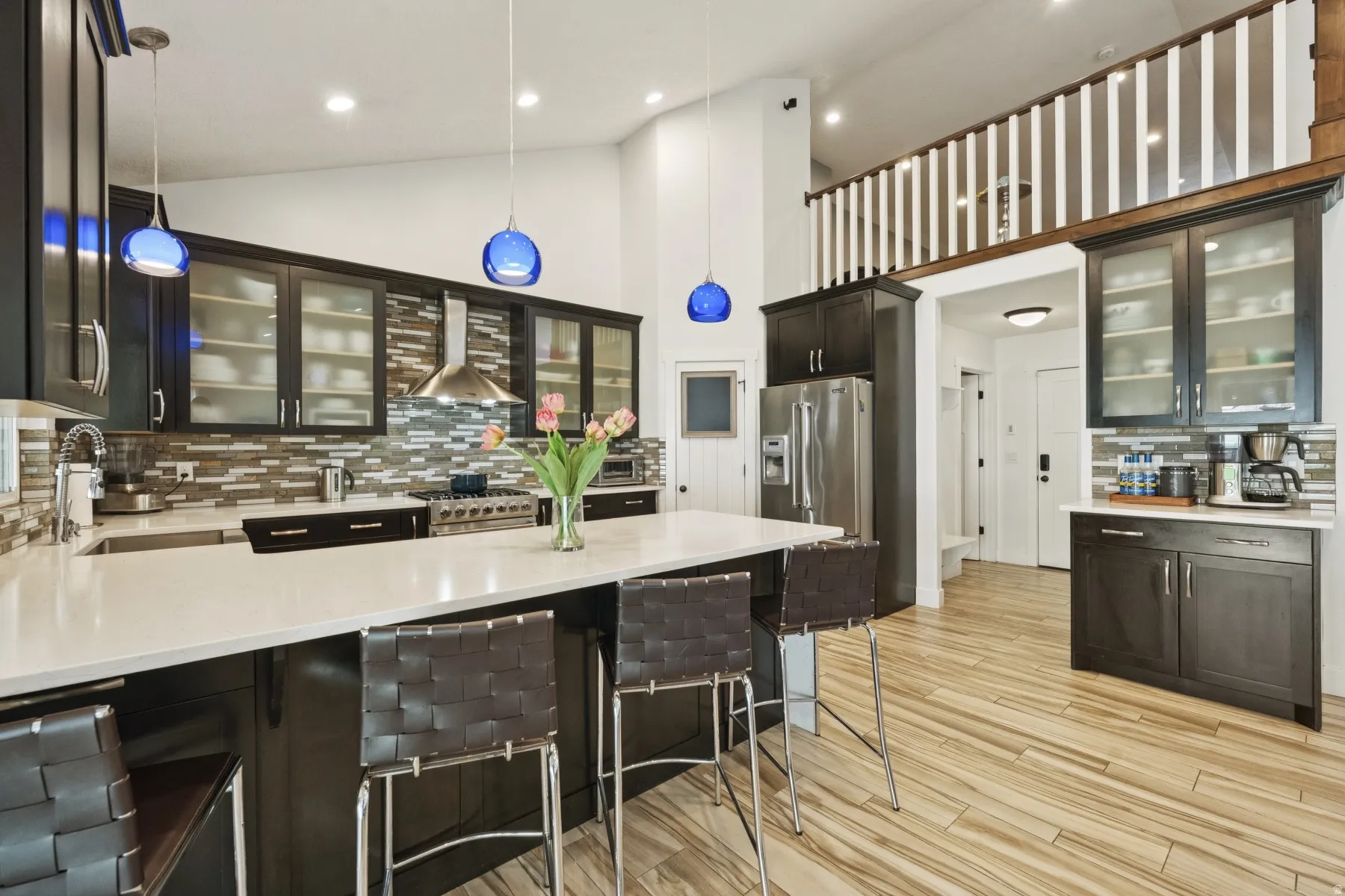 Kitchen featuring glass insert cabinets, tasteful backsplash, a peninsula, light stone countertops, and high end appliances