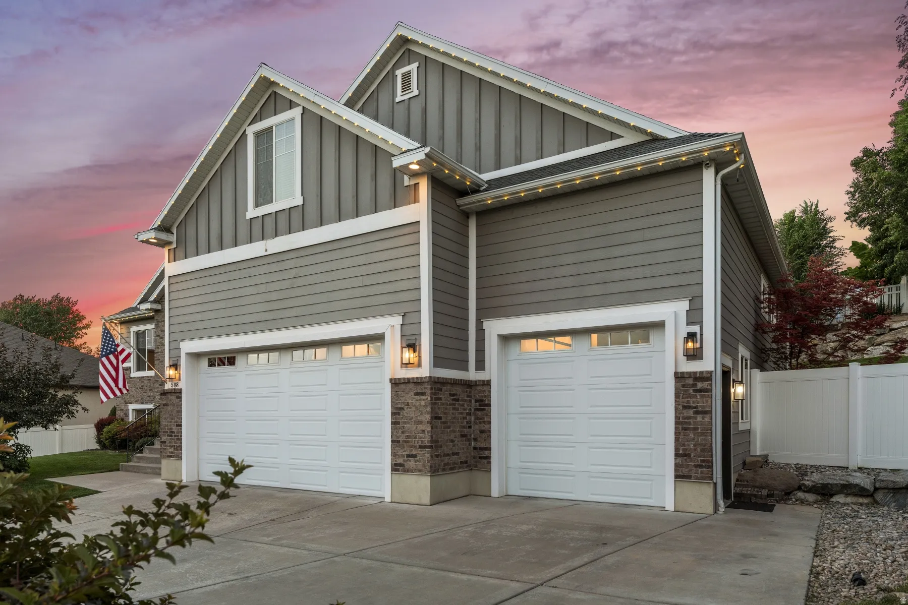 View of front of house with board and batten siding, driveway, a garage, and brick siding
