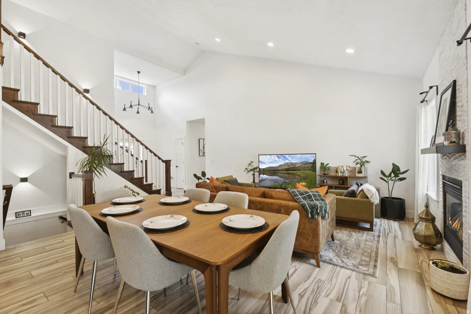 Dining room with light wood-style flooring, a fireplace, hanging lights, and vaulted ceiling