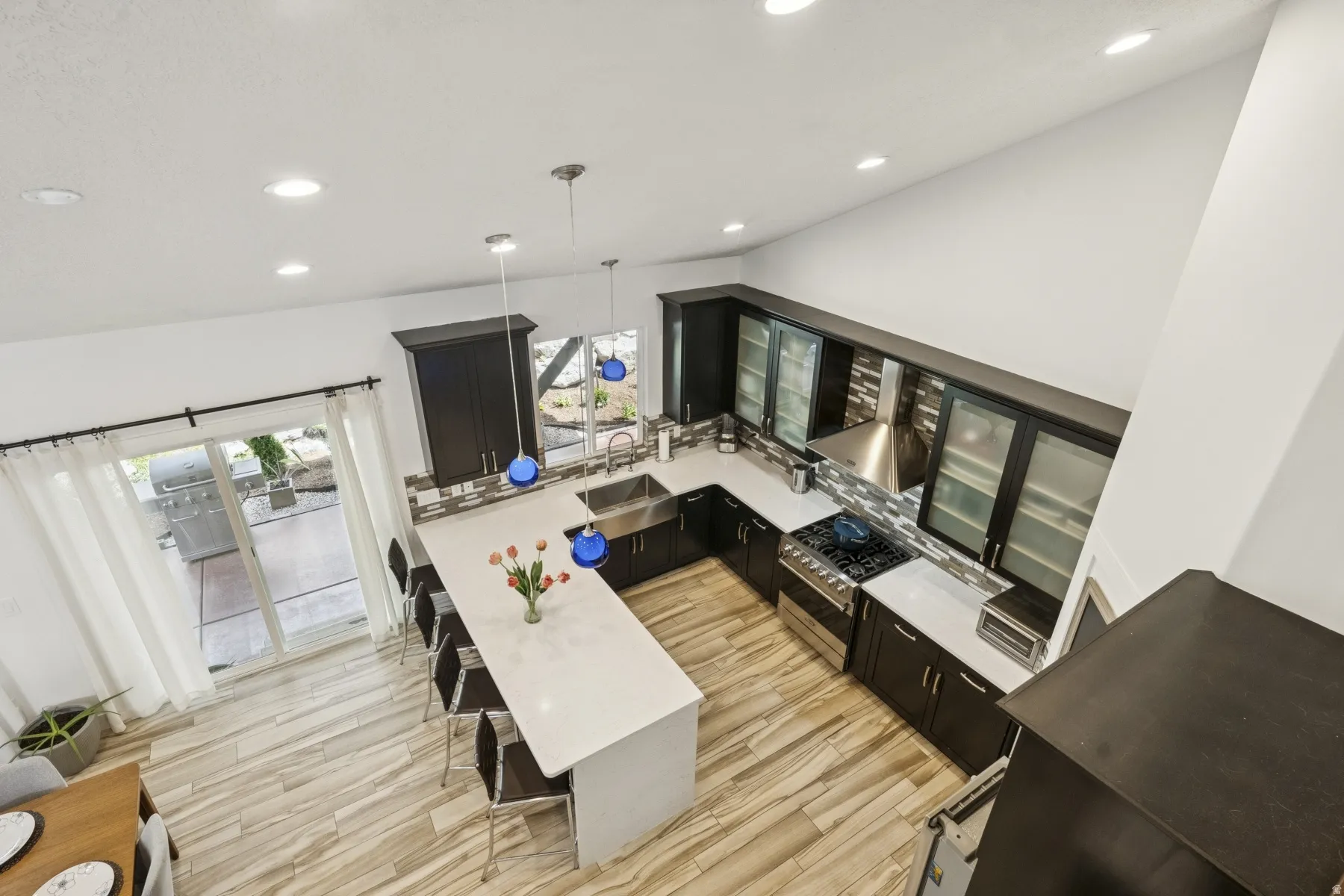 Kitchen featuring dark cabinetry, decorative light fixtures, a kitchen breakfast bar, high end range, and a peninsula