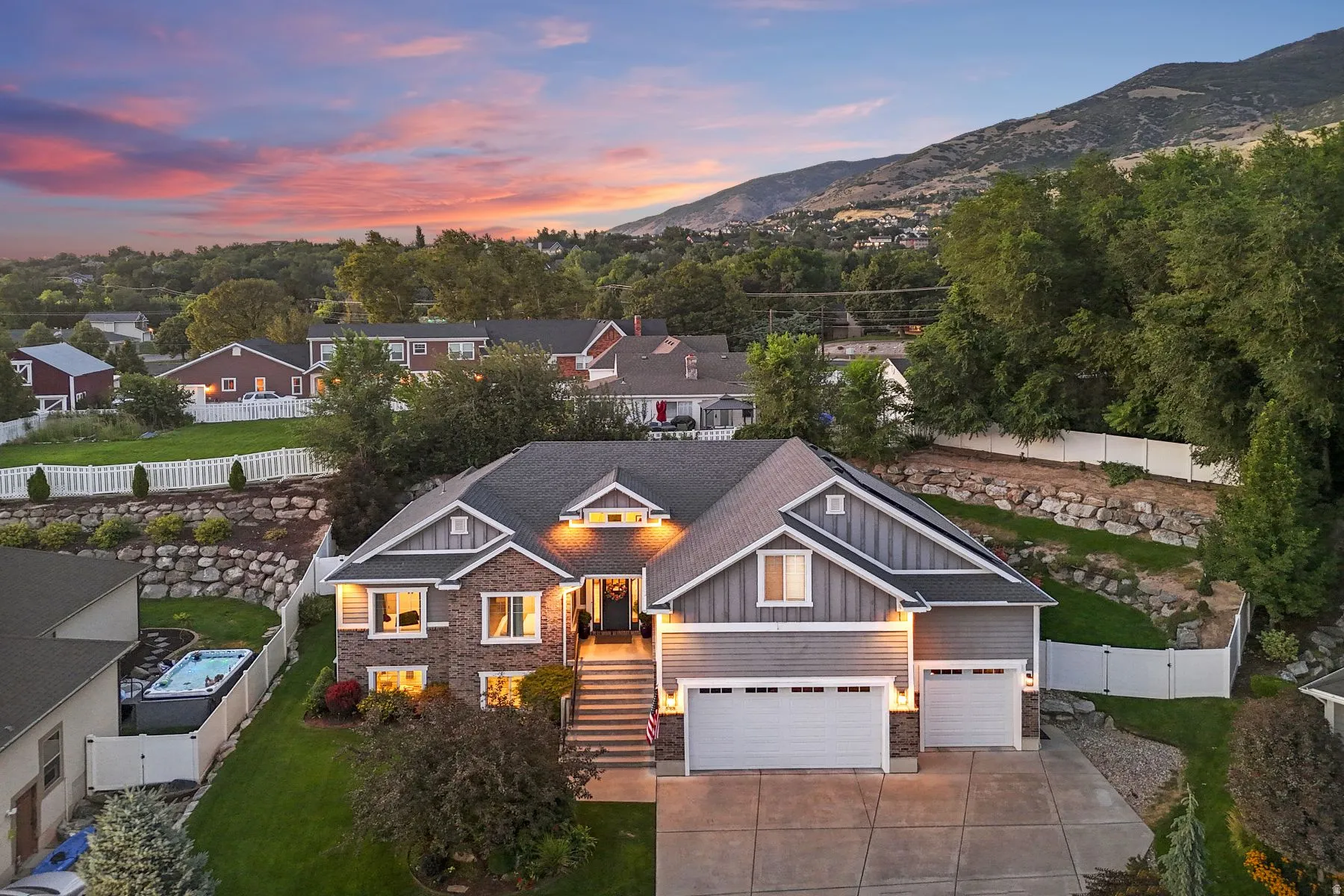 View of front of home featuring board and batten siding, concrete driveway, stone siding, and a gate
