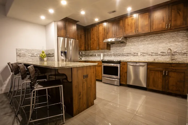 Kitchen featuring wood cabinetry, stainless steel appliances, a tile backsplash, light-toned countertops, and recessed lighting