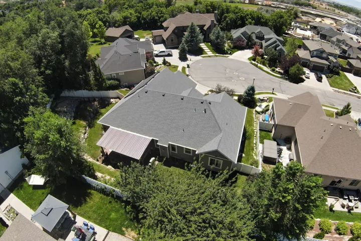 Residential property featuring a dark grey shingle roof, light grey siding, and an attached covered patio with a metal roof