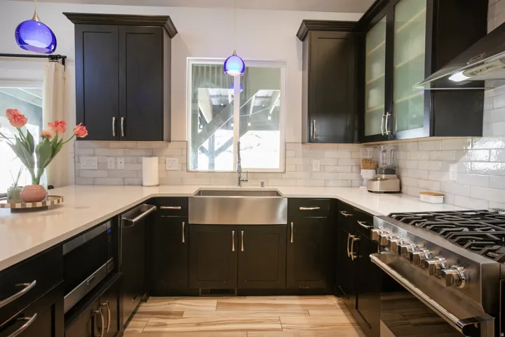 Contemporary kitchen featuring dark cabinetry, light-toned countertops, and a subway tile backsplash