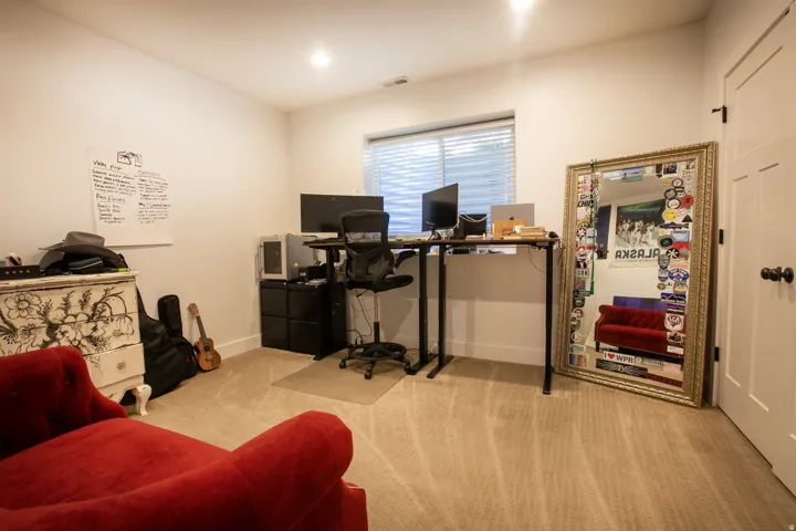 Carpeted room with a window featuring horizontal blinds, recessed lighting, and a white paneled door with dark hardware