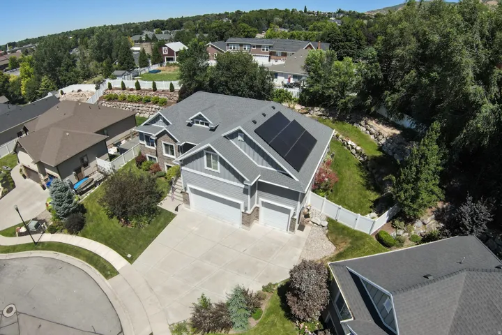 Gray two-story residence featuring a two-car garage, solar panels, and a concrete driveway