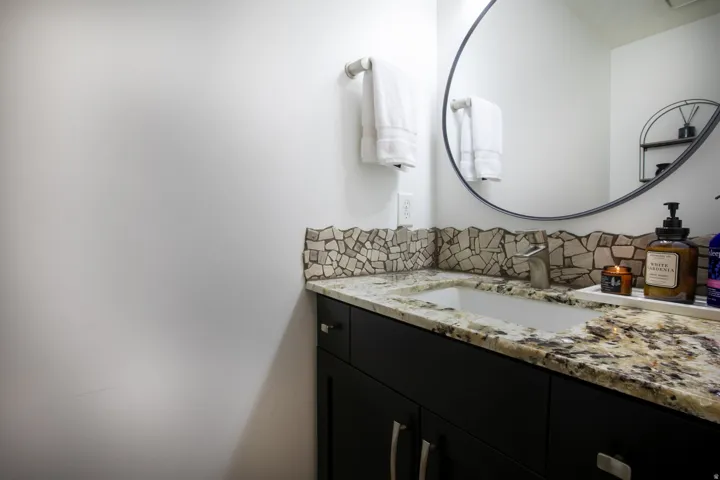 Vanity with a granite countertop, undermount sink, and black cabinetry