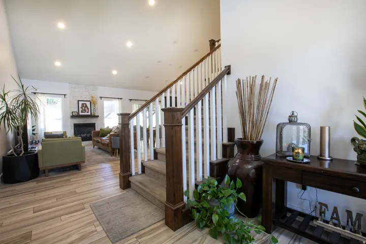 Inviting entryway with wood-finish flooring and a staircase featuring dark wood newel posts and white balusters
