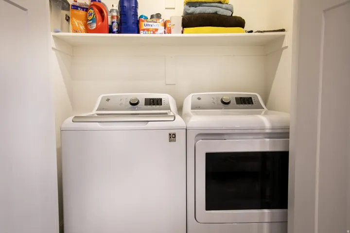 Dedicated laundry closet featuring a white top-load washing machine and a white front-load dryer