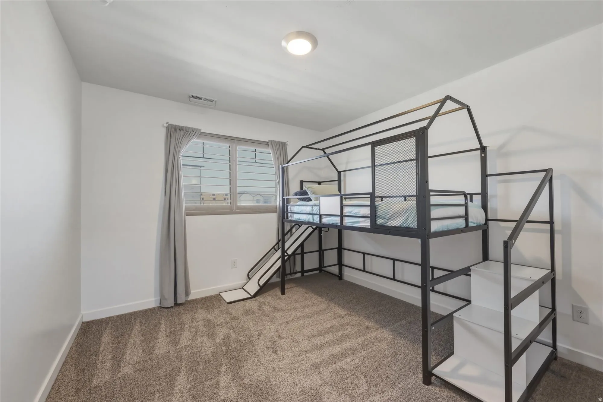 Carpeted room with a double-pane window featuring grey drapes