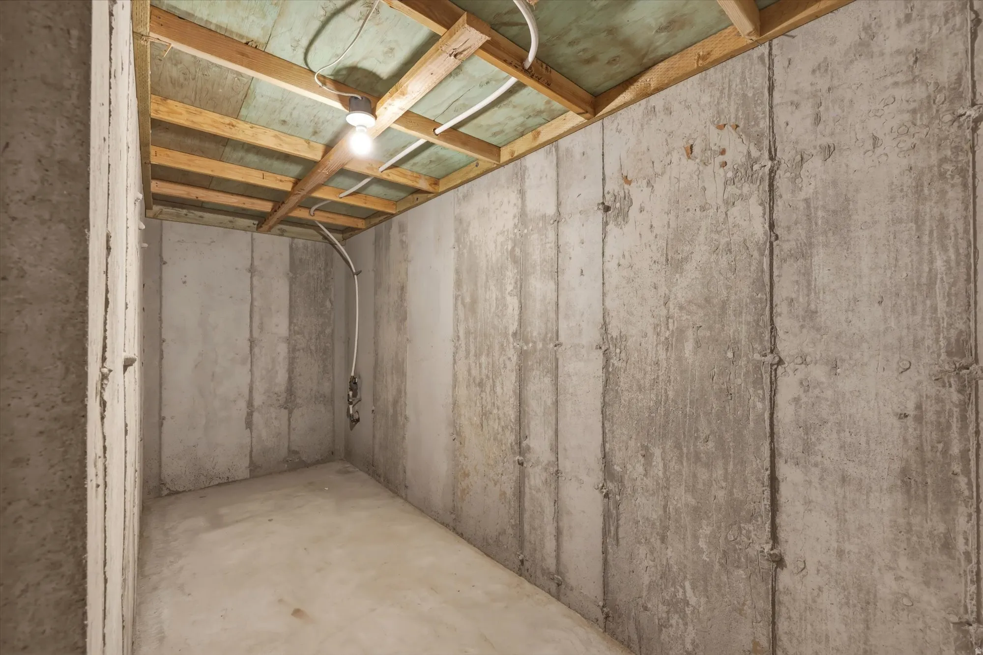 Unfinished lower level featuring concrete slab flooring and exposed ceiling joists
