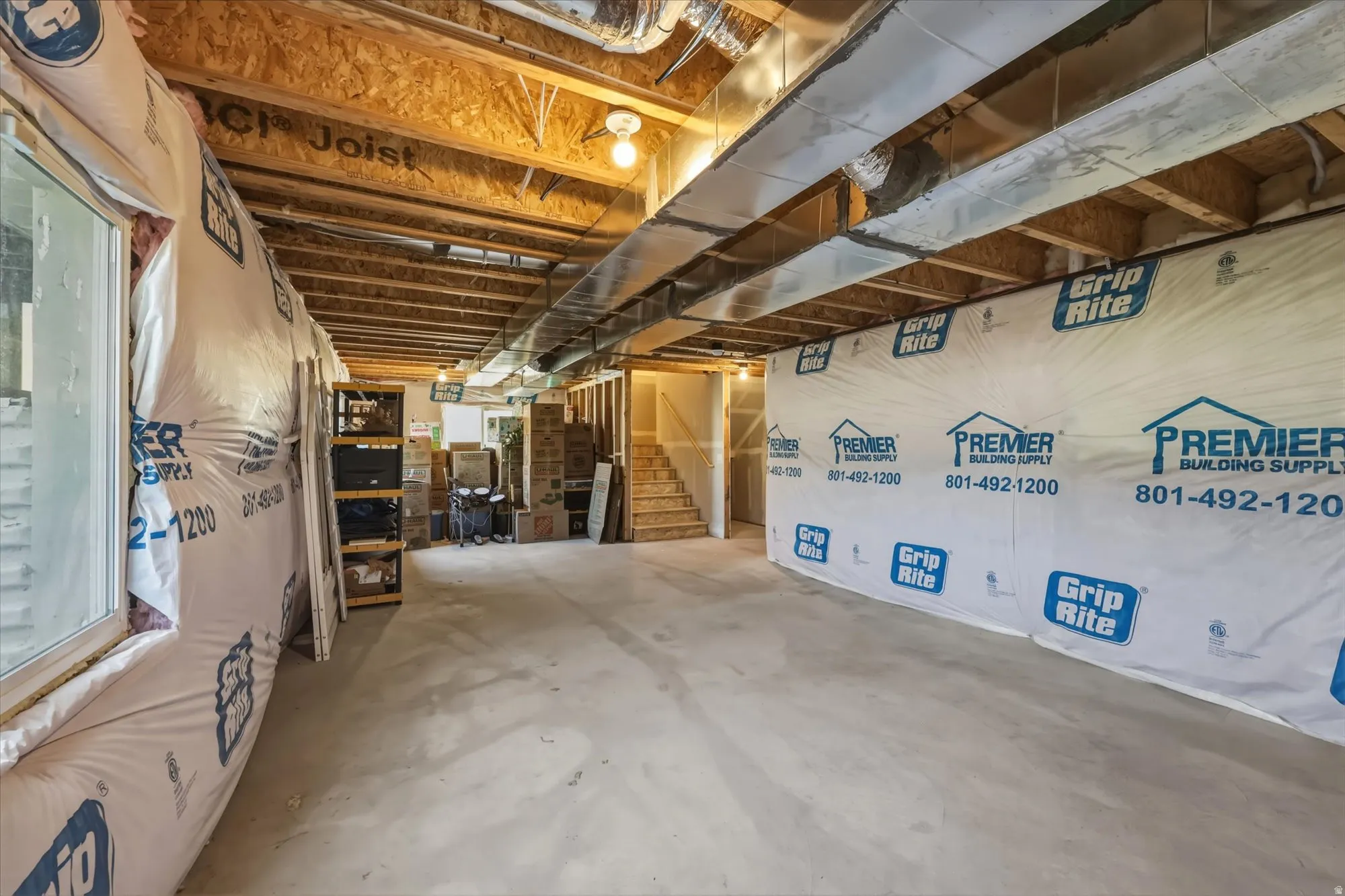 Unfinished basement with concrete flooring, exposed joists, and visible ductwork