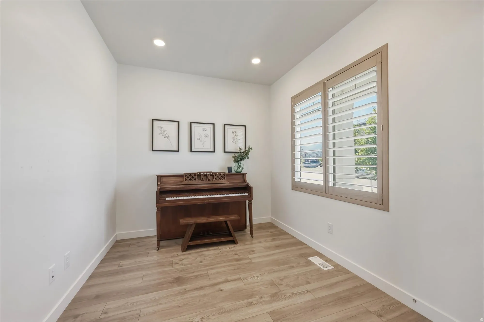 Recessed lighting illuminates this bright space, featuring wood-finish flooring and white baseboards