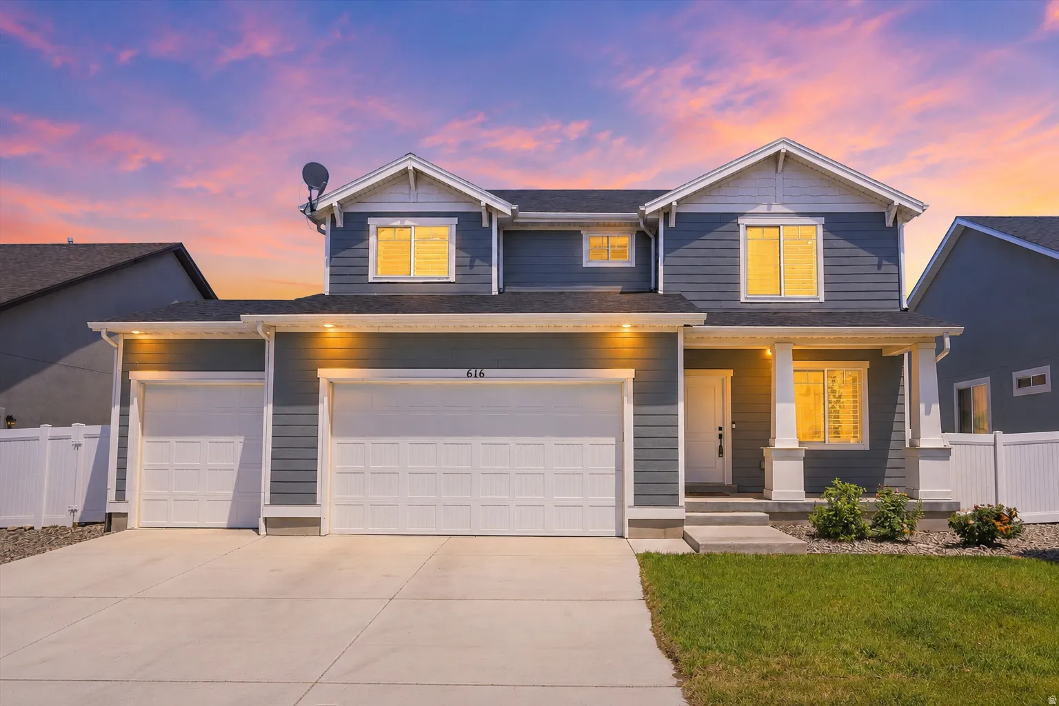 Two-story residence featuring a dark gray siding exterior with white trim accents and a white picket fence