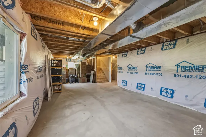 Unfinished basement with concrete flooring, exposed joists, and visible ductwork