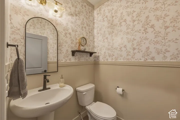 Pedestal sink with a matte black faucet, complemented by a black-framed arched mirror