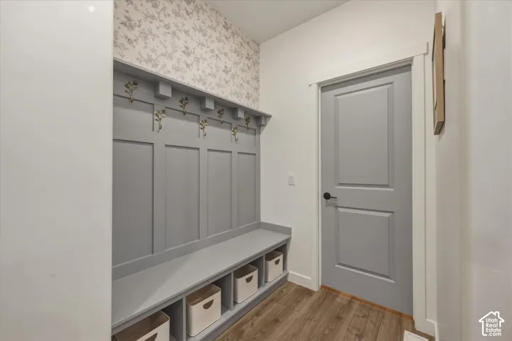 Built-in entryway storage bench with paneled wainscoting and decorative hooks, complemented by patterned wallpaper