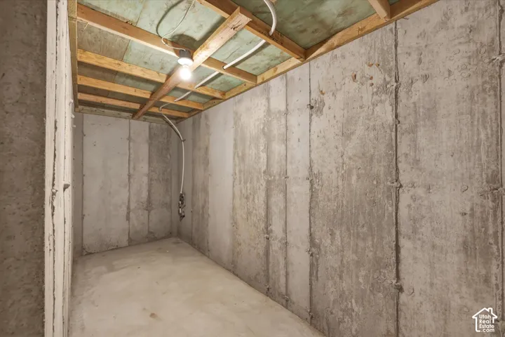 Unfinished lower level featuring concrete slab flooring and exposed ceiling joists