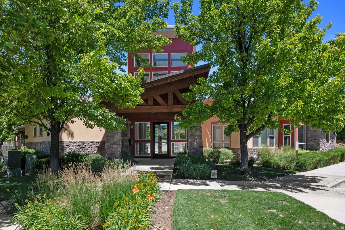 Contemporary exterior featuring stone veneer, stucco siding, and a prominent wood-beam entry canopy