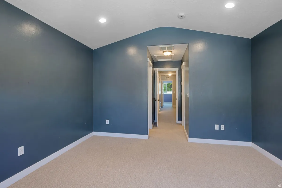 Carpeted room featuring blue walls, white trim, recessed lighting, and a sloped ceiling