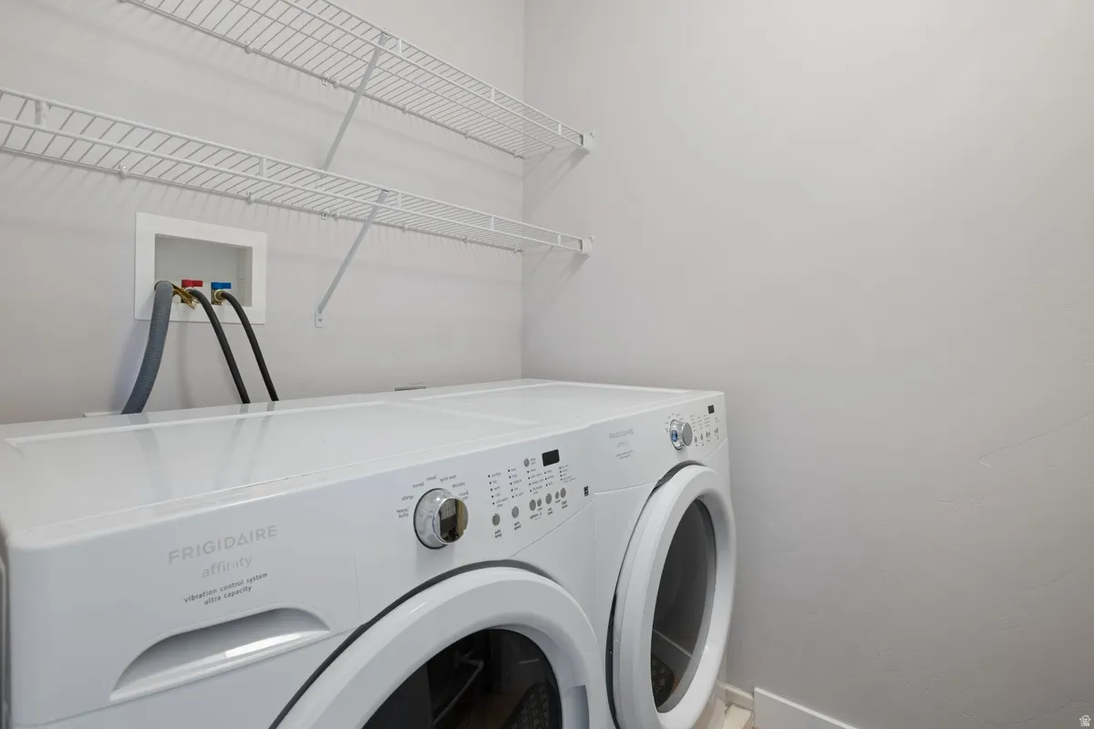 Laundry area featuring white wire shelving, a front-loading washer and dryer, and a built-in utility box with hookups