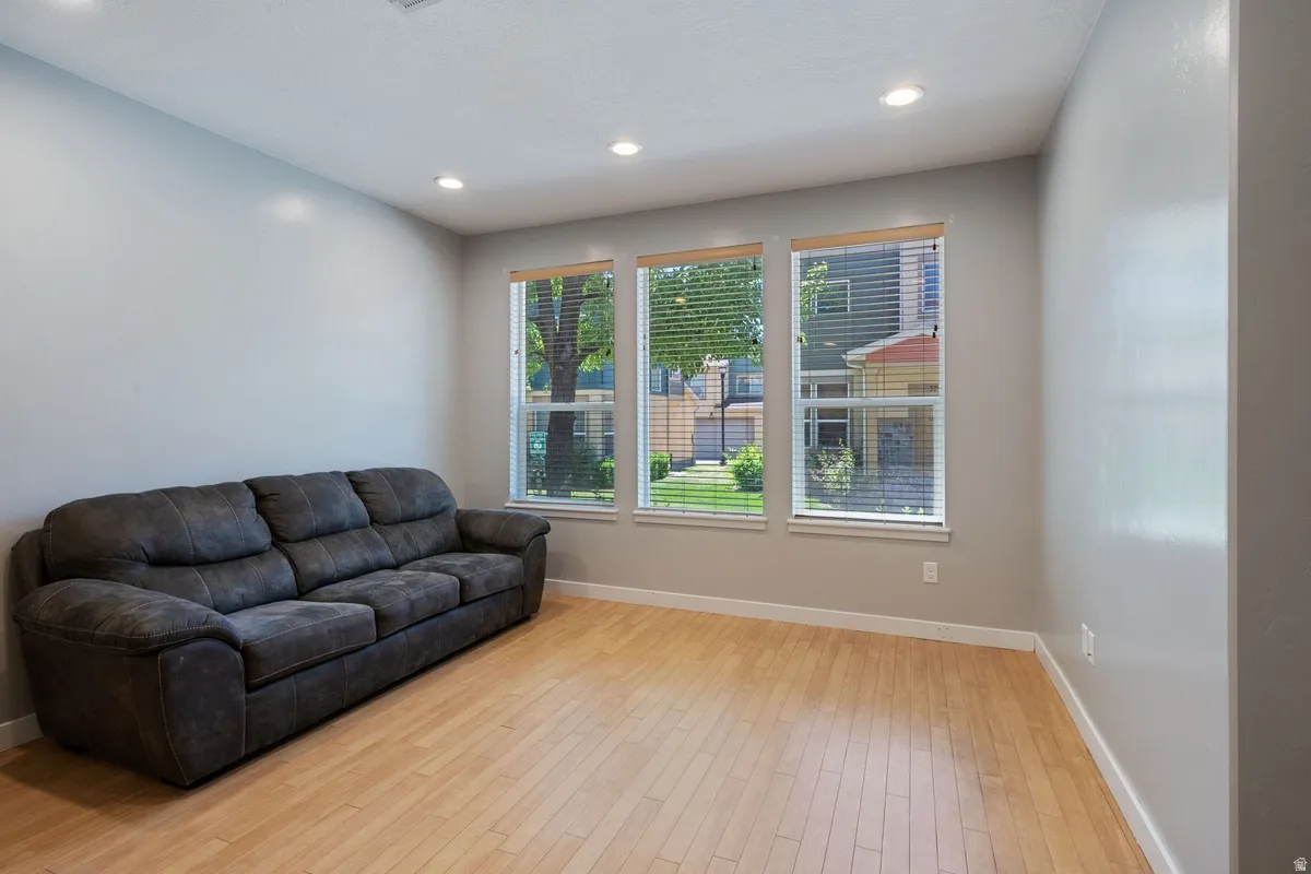 Bright interior space featuring wood-finish flooring, recessed lighting, and a trio of windows with horizontal blinds