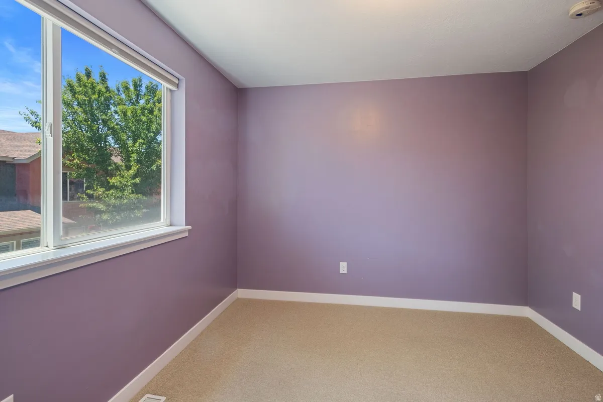 Interior room with purple-painted walls, a large window, and beige carpeting