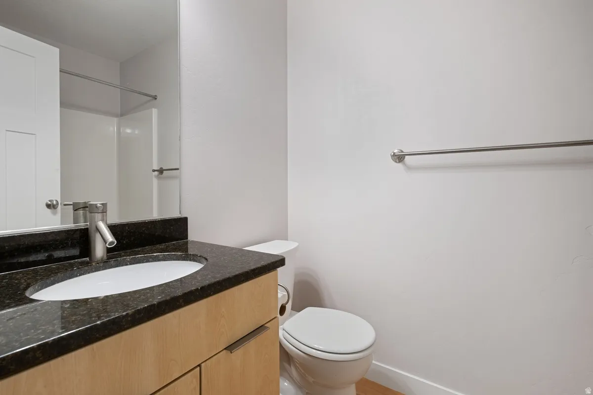 Bathroom vanity featuring a dark stone countertop with an undermount sink and a brushed nickel faucet