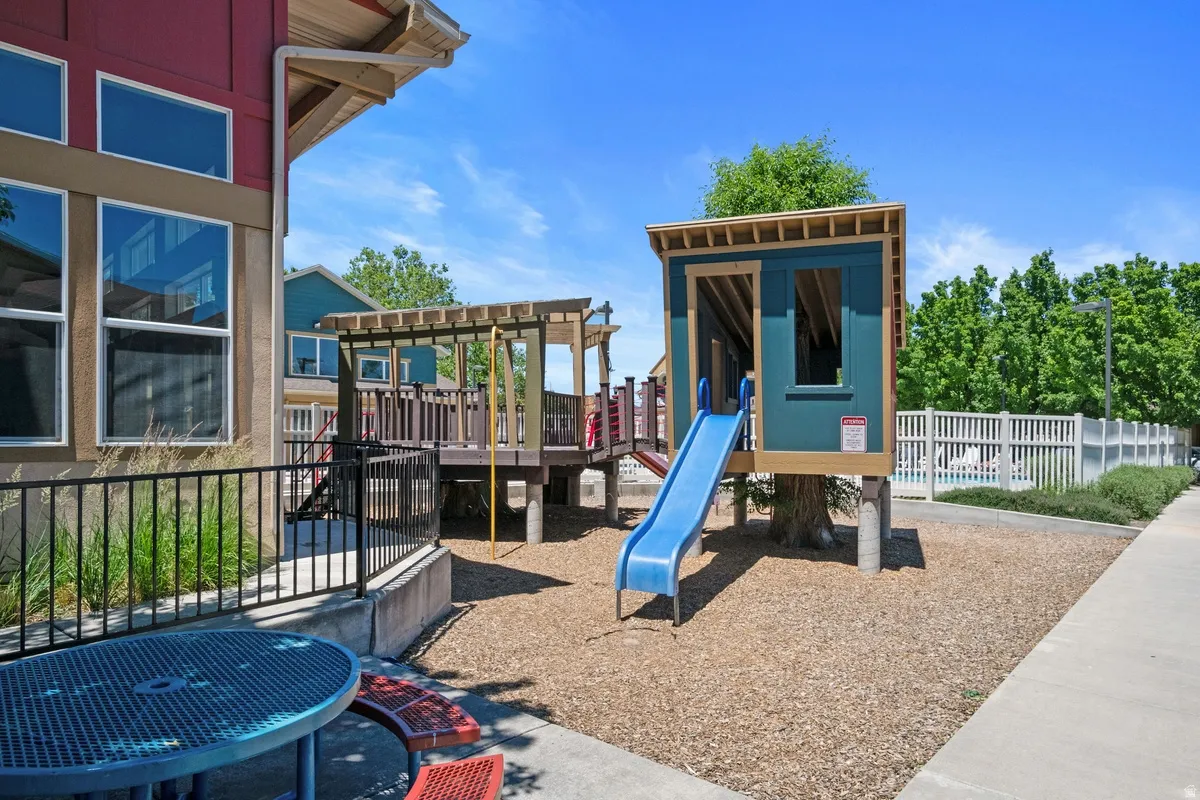 Outdoor recreational area featuring a play structure with a blue slide, a secondary elevated platform, and a wood chip surface