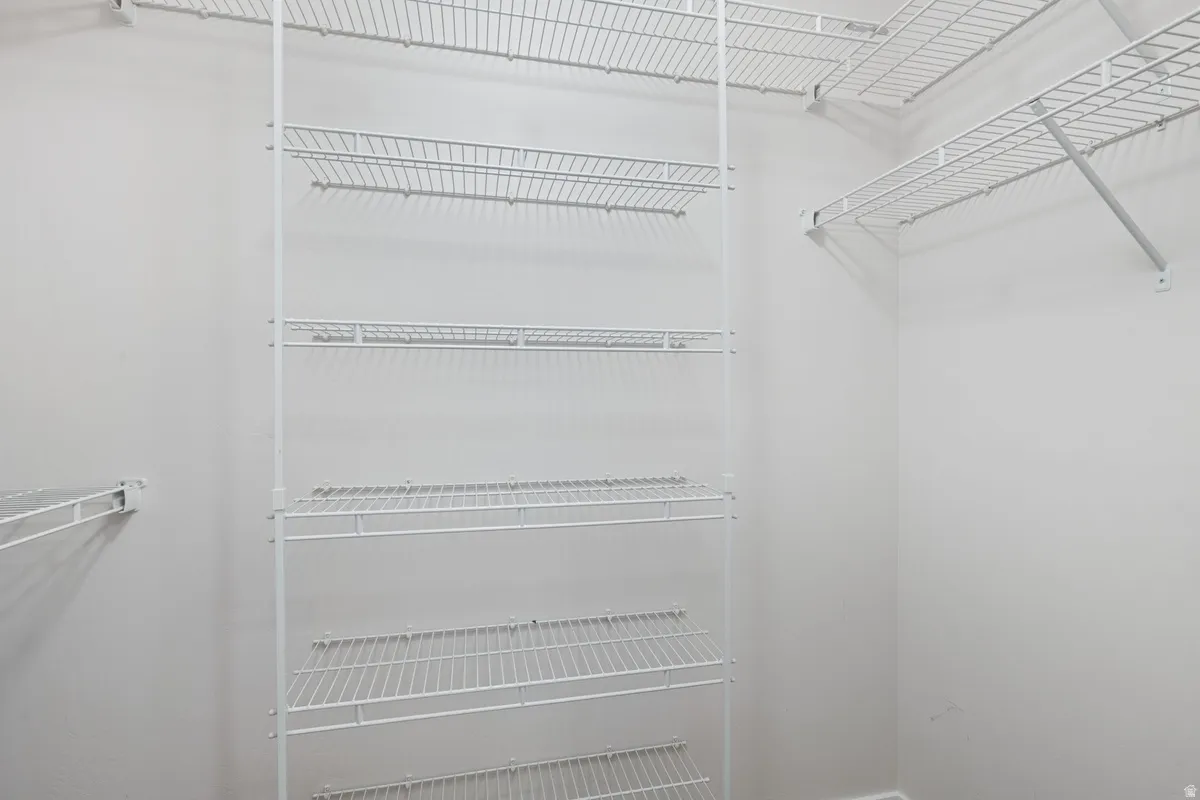 Walk-in closet featuring white wire shelving, full-height storage racks, and corner shelving units