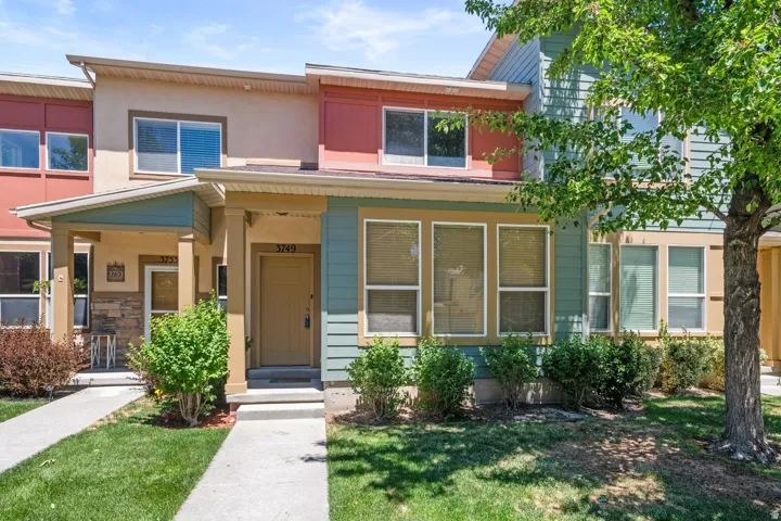 Two-story townhouse with a multi-toned facade, featuring a covered entry porch with stone accents