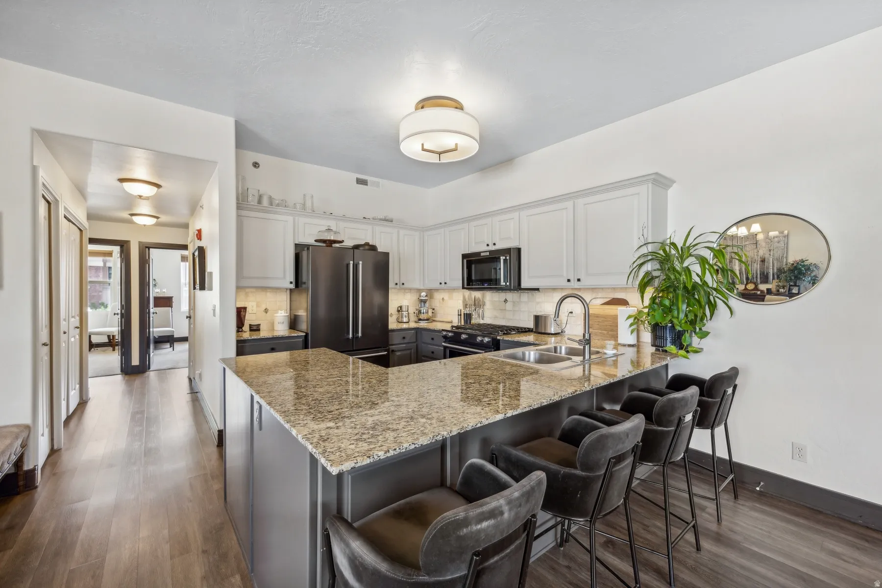 Kitchen featuring an expansive island with a granite countertop, undermount sink, and seating for multiple individuals