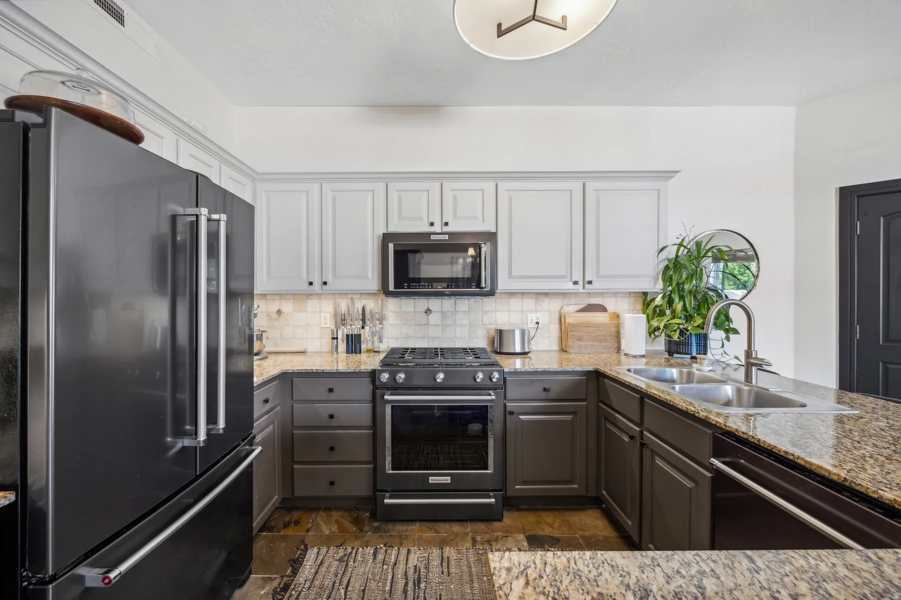 Kitchen featuring a black stainless steel refrigerator, granite countertops, and a dual-basin stainless steel sink with a gooseneck faucet