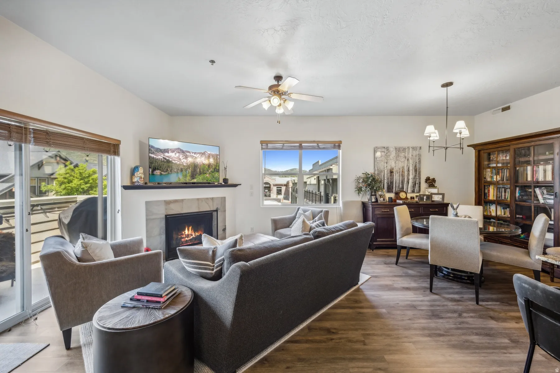 Spacious living area featuring wood-finish flooring, a tile-surround fireplace with a dark mantel, and recessed lighting
