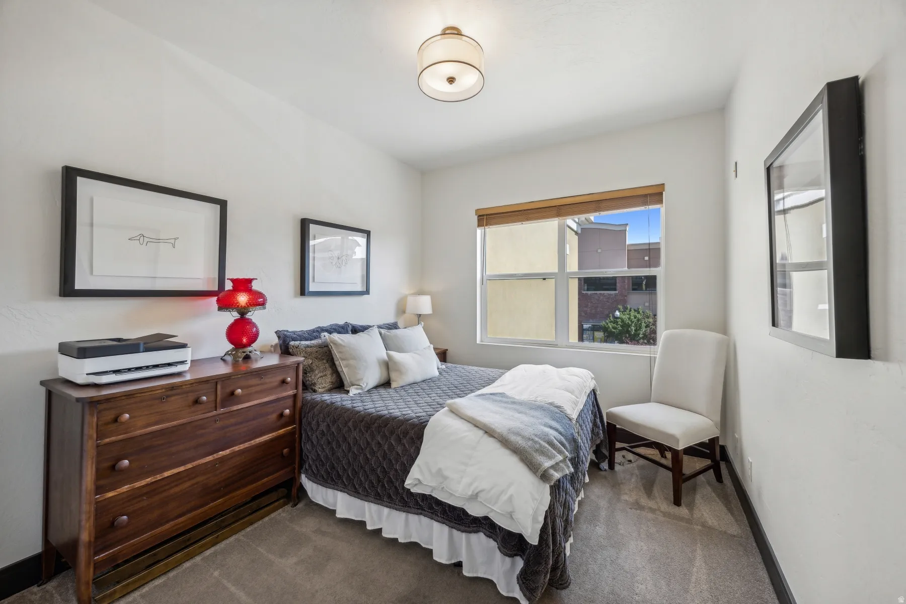Carpeted room featuring a double window with wood-finish blinds, white painted walls, and a ceiling-mounted drum light fixture