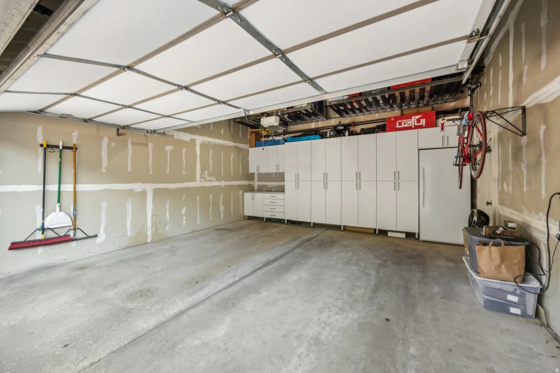 Attached garage featuring an overhead garage door, built-in white cabinetry, a built-in refrigerator, and concrete flooring