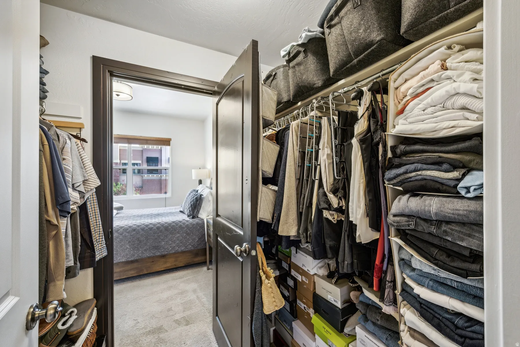Walk-in closet featuring extensive built-in shelving, multiple hanging rods, and an overhead storage shelf