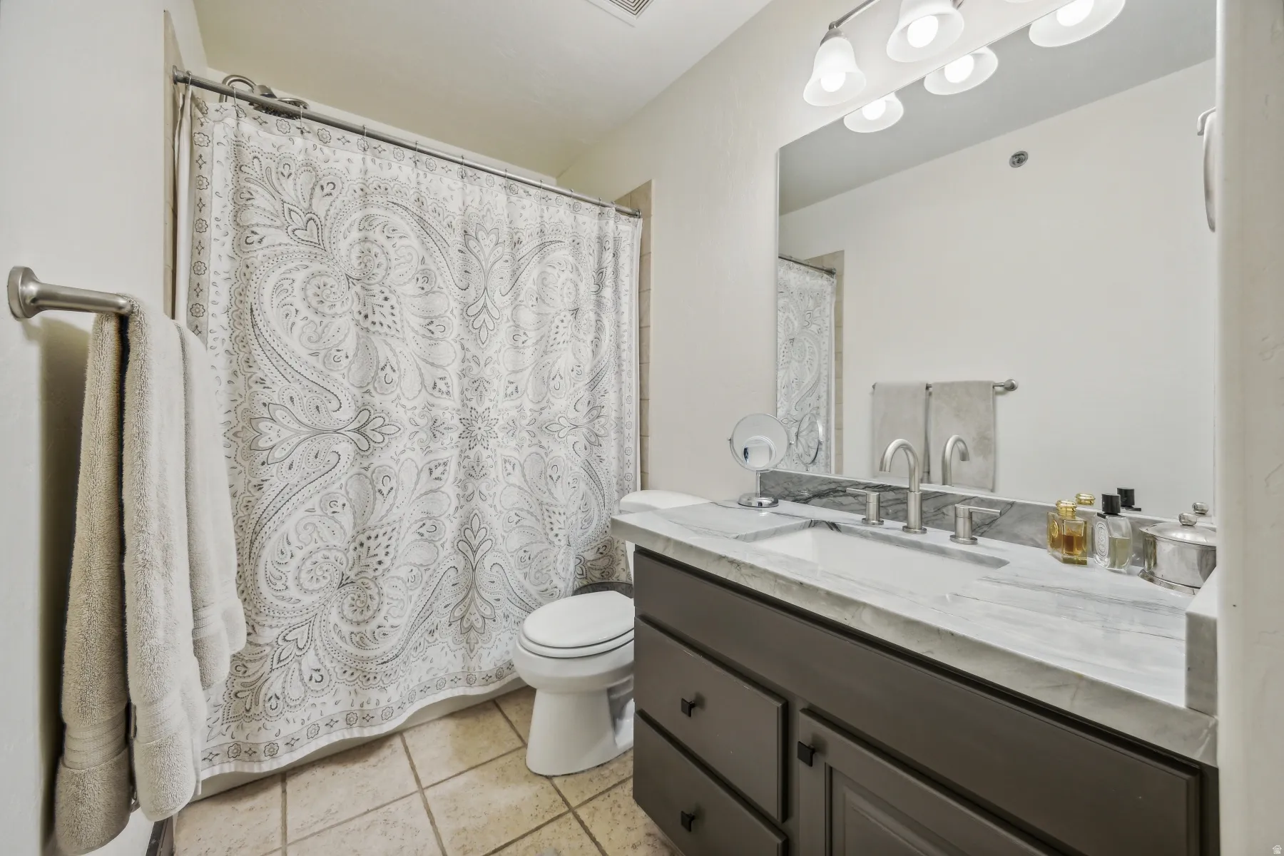 Bathroom featuring a single vanity with a light-toned countertop, a mounted mirror, and an overhead light fixture